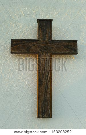 Old wooden cross on the white wall in sunlights