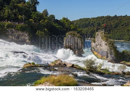 Waterfall on the river Rhine Schaffhausen Switzerland. Rhine Falls is the largest waterfall in Europe in summer day against blue sky