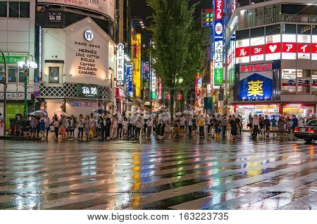 Tokyo Japan - August 29 2016: People at pedestrian crossing in Kabukicho Ichibangai with world famous fashion brand stores on the background. Text in Japanese advertises clothing goods and services