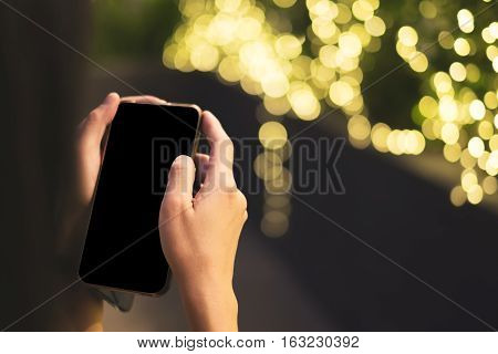Woman Hand Holding Mobile With Black Blank Screen With Light Bokeh Background,digital Lifestyle,mock