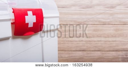 White Case with red clasp and a white cross. Wooden table background