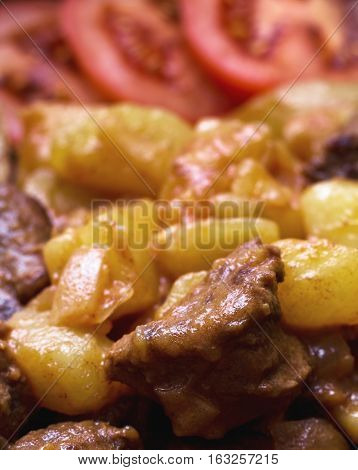 The second dish - bubble and squeak. Tomatoes in the background. Close-up.