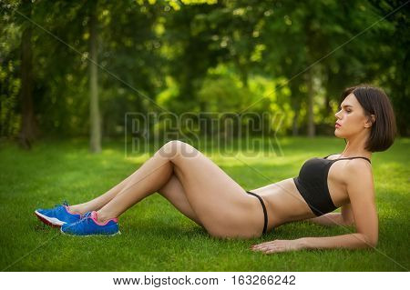 woman doing abs workout on the grass in the Park