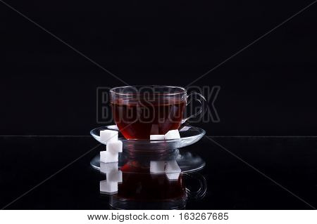 Cup Of Black Tea With Slices Of Sugar On A Black Background