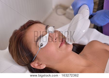Pretty young woman getting cryolipolyse treatment in professional cosmetic cabinet