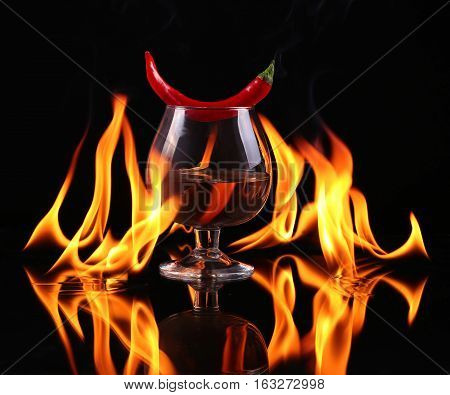 Hot Chili Pepper In A  Cognac Ballon With A Fire On A Black Background