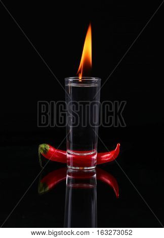 Hot Chili Pepper In A Shot  Glass With A Fire On A Black Background