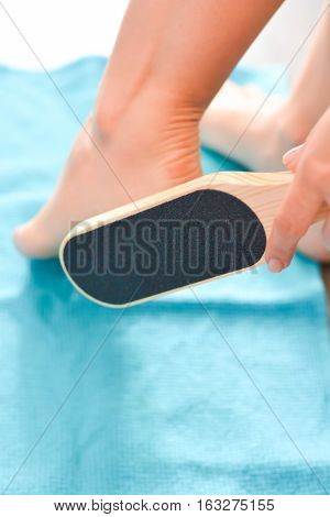 Female hand holding a foot file near her heel