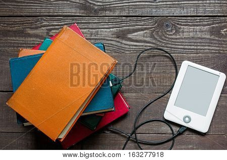 ebook and old books on wooden table. tablet download information from many books. new technology concept. top view