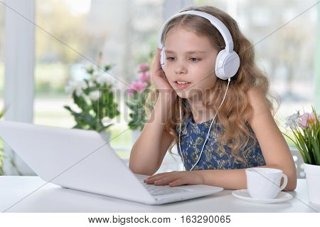 cute girl listening to music using headphones and laptop