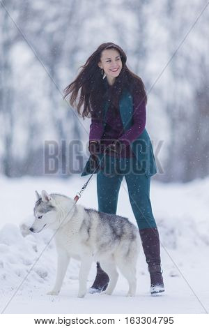 Portrait of Smiling and Happy Caucasian Woman Airing Her Husky Dog Outdoors in Forest.Vertical Image