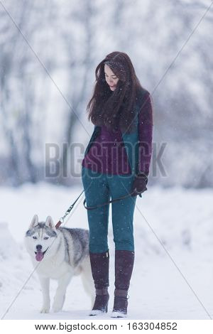 Portrait of Smiling and Happy Caucasian Woman Airing Her Husky Dog Outdoors in Forest.Vertical Shot