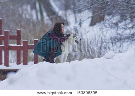 Portrait of Pretty Tranquil Caucasian Brunette With Her Husky Dog during a Stroll in Winter.Horizontal Image