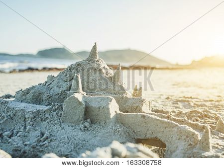 Sand castle on the beach after sea storm in sardinian beach - Holiday and vacation concept on seaside in Italy at sunset time - Focus on top construction tower - Warm filter with sun flare