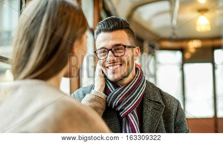 Young couple having tender moments inside old style tram bus - Girlfriend cuddling his boyfriend indoor - Concept of lovesweetness and relationship - Focus on man glasses eye - Warm filter