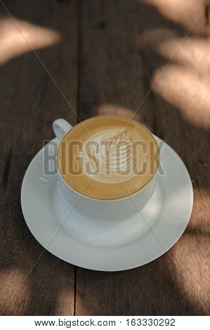 Cup of hot Cappuccino art coffee on wooden table