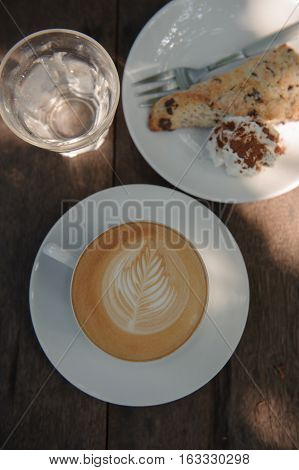 Cup of hot Cappuccino art coffee on wooden table