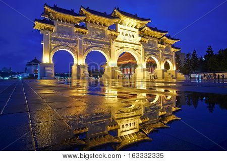 Asia culture - night view of Liberty Square (Archway of Chiang Kai Shek Memorial Hall) with reflection in raining day Taipei Taiwan. the Chinese text on the archway : Liberty Square
