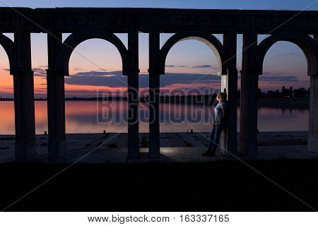 Young woman relaxing on the lake at sunset. Lonely woman enjoy watching sunset over the city lake in Bucharest