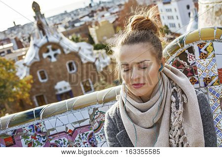 Woman Listening Audioguide While Sitting On Bench In Barcelona