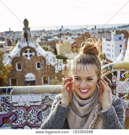 Woman In Barcelona Listening Audioguide While Sitting On Bench