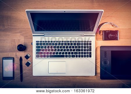 Workplace of phrographer. Laptop pen tablet SD Cards smartphone and compact camera. Postproduction and digital editing concept.