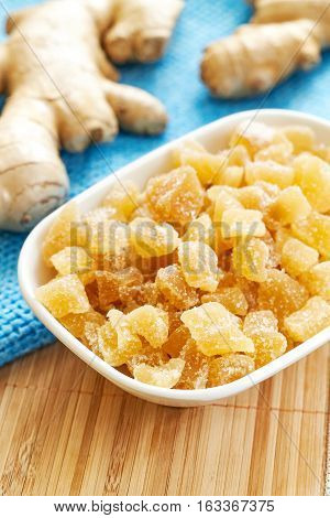 Candied ginger in white bowl on wooden table