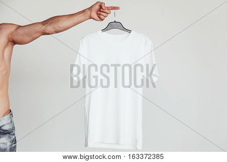 Guy with naked torso holding a white T-shirt in his hands. Branding Mock-Up