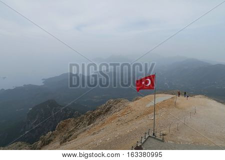 Turkish Flag at the Top of the Tahtai Dagi - Olympos Mountain in Kemer with Olympos Beach in the Background and the Mediteranian Sea