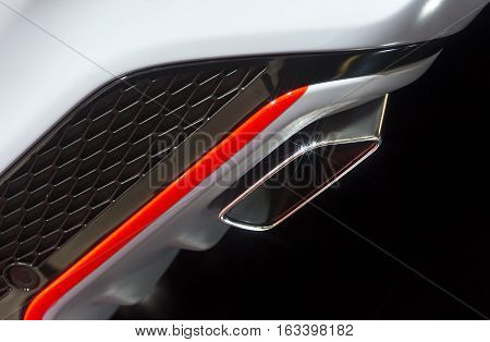 Chrome exhaust pipe of powerful sport car with white bodywork, orange and grey steel and plastic details