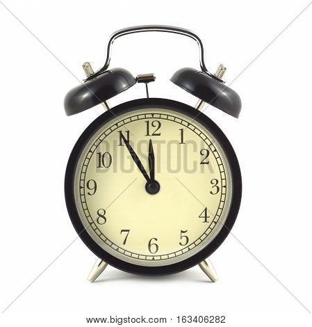Alarm clock in black case and beige clockface shows 5 minutes to twelve isolated on white close up