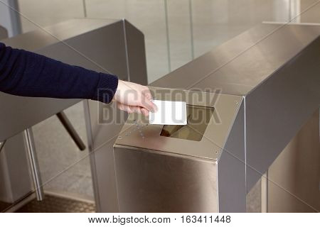 Woman's hand puts white plastic card to reader access security control system closeup