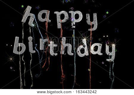 Happy Birthday. Happy birthday in silver glitter party text with streamers stars and fireworks effect. Ideal birthday card party invitation or poster image.