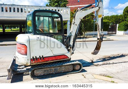 Mini excavator with narrow bucket for laying fiber-optic cable line