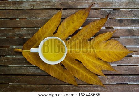 Jasmine tea cup on wooden table above yellow leaf