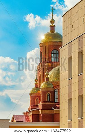 Sunny glitter of golden domes of the Cathedral displayed due to the corner of the building. Stroitel town.