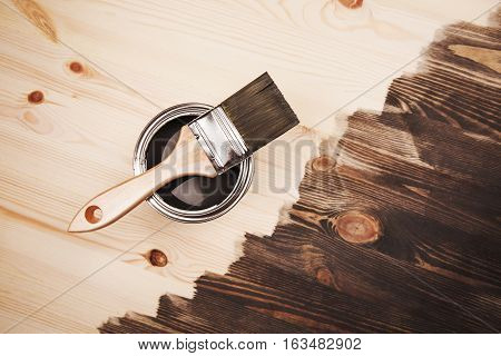 Paint brush on the can lying on wooden background. The surface is half - toned with grey color.