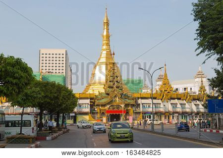 YANGON MYANMAR - NOVEMBER 26 2016: some cars and traffic in the downtown of Yangon Myanmar with the Sule pagoda in the background