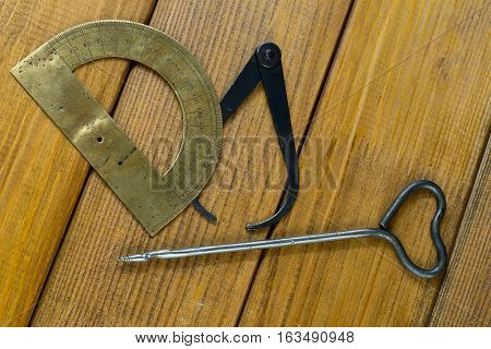 one old gimlets, hand-tools for drilling holes in wood, calipers, protractor. Brown plywood background