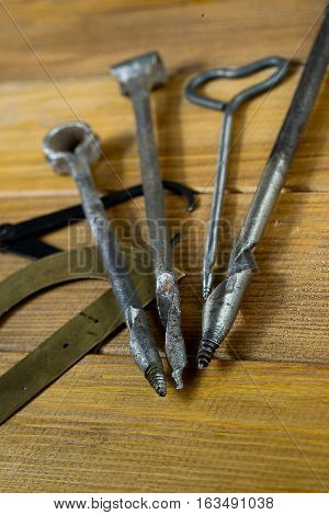 Several old gimlets, hand-tools for drilling holes in wood, calipers, protractor. Brown plywood background