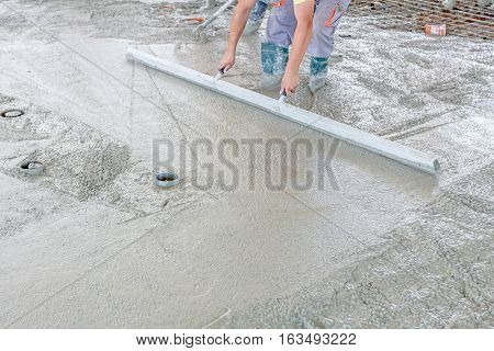 Mason is using a trowel to finish top of the concrete foundation.