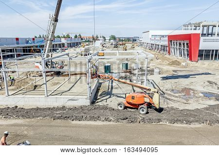 Above view on building site cherry picker has elevated platform with riggers in safety basket.