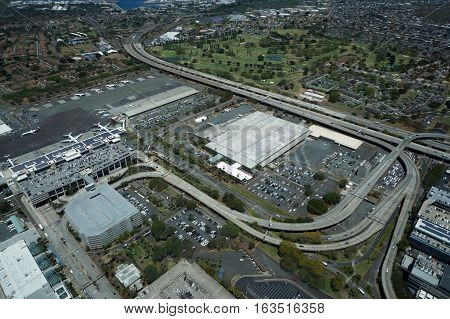 HONOLULU - APRIL 20: Aerial view of planes helicopters Golf Course Parking lots Roads leading into Airport and cars parked by buildings at the Honolulu International Airport HNL next to the water on Oahu Hawaii. April 20 2016.