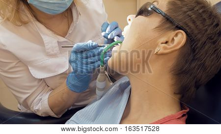 Woman at the dentist clinic office gets dental medical examination and treatment. Close up shot. Odontic and mouth health is important part of modern human life that dentistry help with.