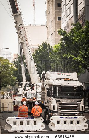 construction workers sit on the barrier during the breaking time next to the crane truck, and they are talking on the building renovating project that they do.