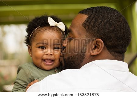 African American loving father holding his daughter.