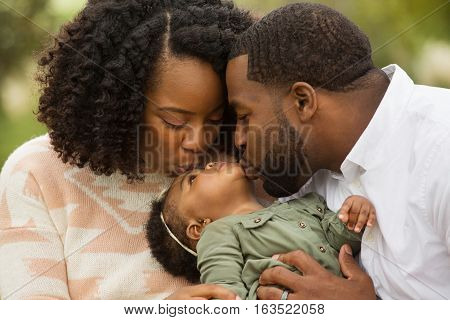 African American Family playing and laughing with their daughter.