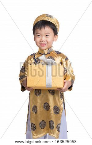 Vietnamese little boy in traditional Aodai, holding a gold gift standing isolated on white background