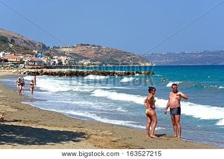 KALYVES, CRETE - SEPTEMBER 16, 2016 - Tourists relaxing on the beach with views towards the mountains Kalyves Crete Greece Europe, September 16, 2016.