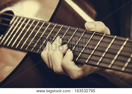 Music sound passion concept. Man playing on acoustic guitar studio shot black background sepia vintage colors